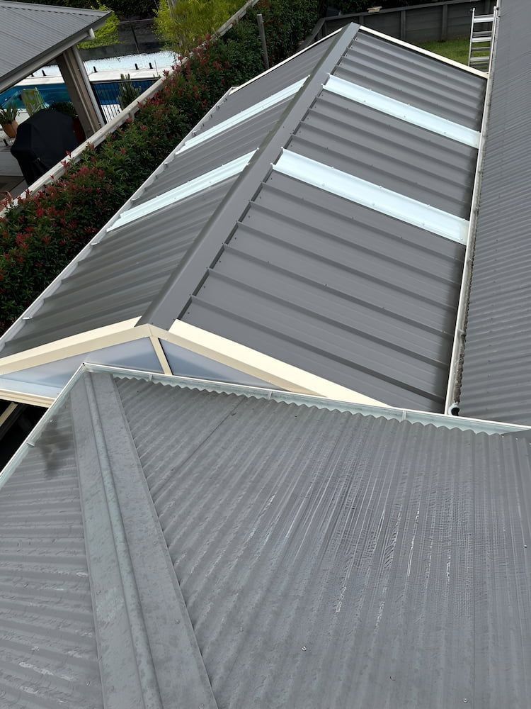 Two gray metal roof sections with skylights, viewed from above at an angle