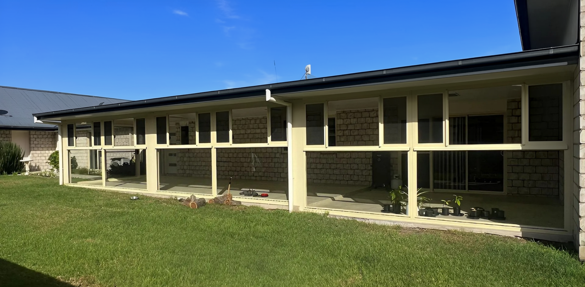 Single-story beige building with a covered porch and green lawn under a clear blue sky