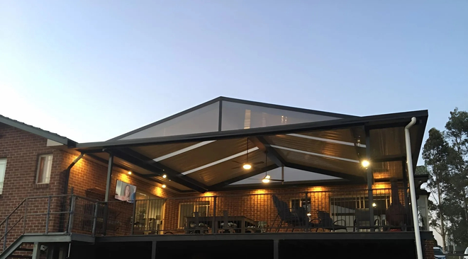 Covered driveway beside a white building with a carport, garage door, and grassy roadside