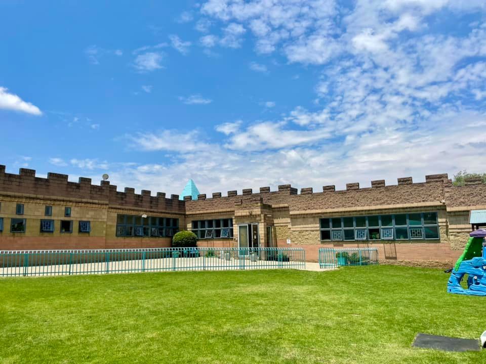 A large brick building with a playground in front of it.