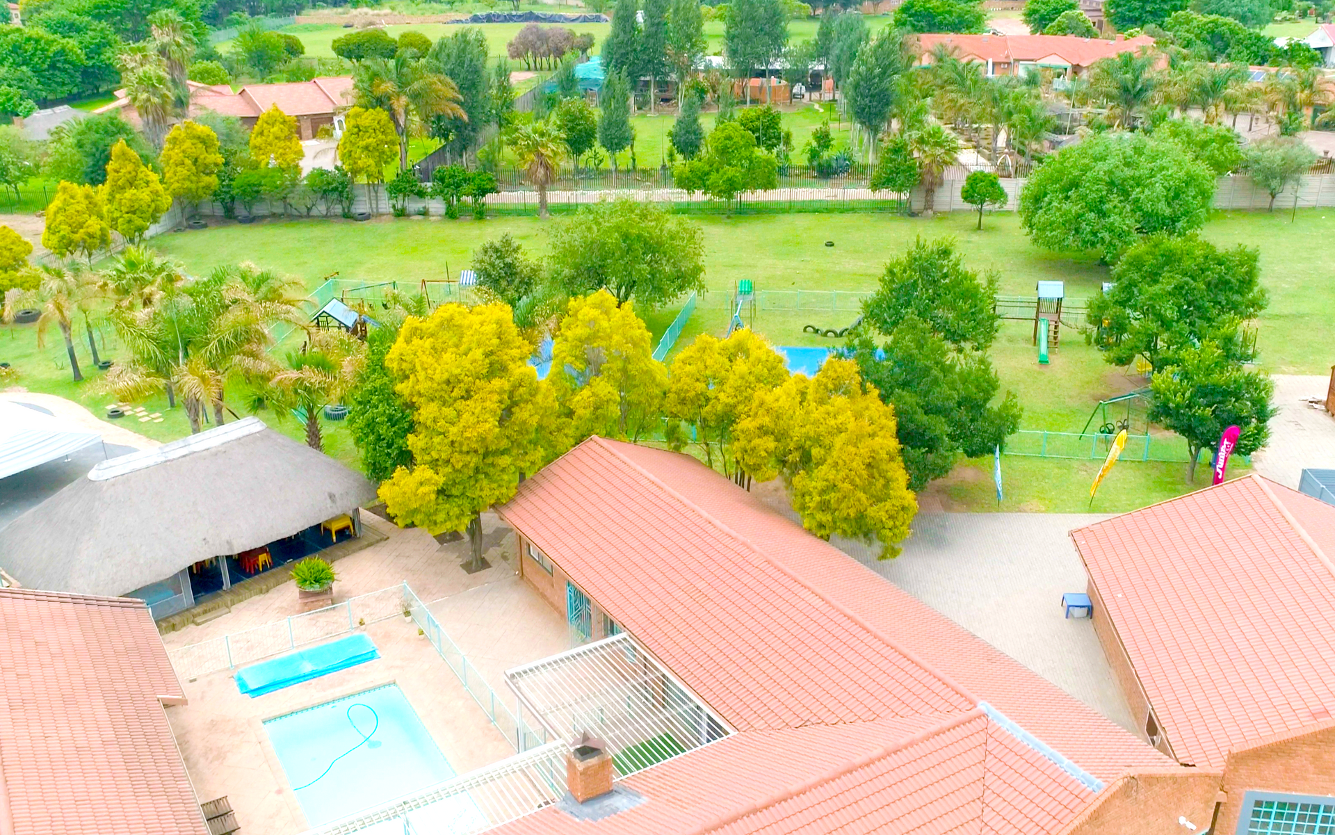 An aerial view of a swimming pool surrounded by trees and buildings.