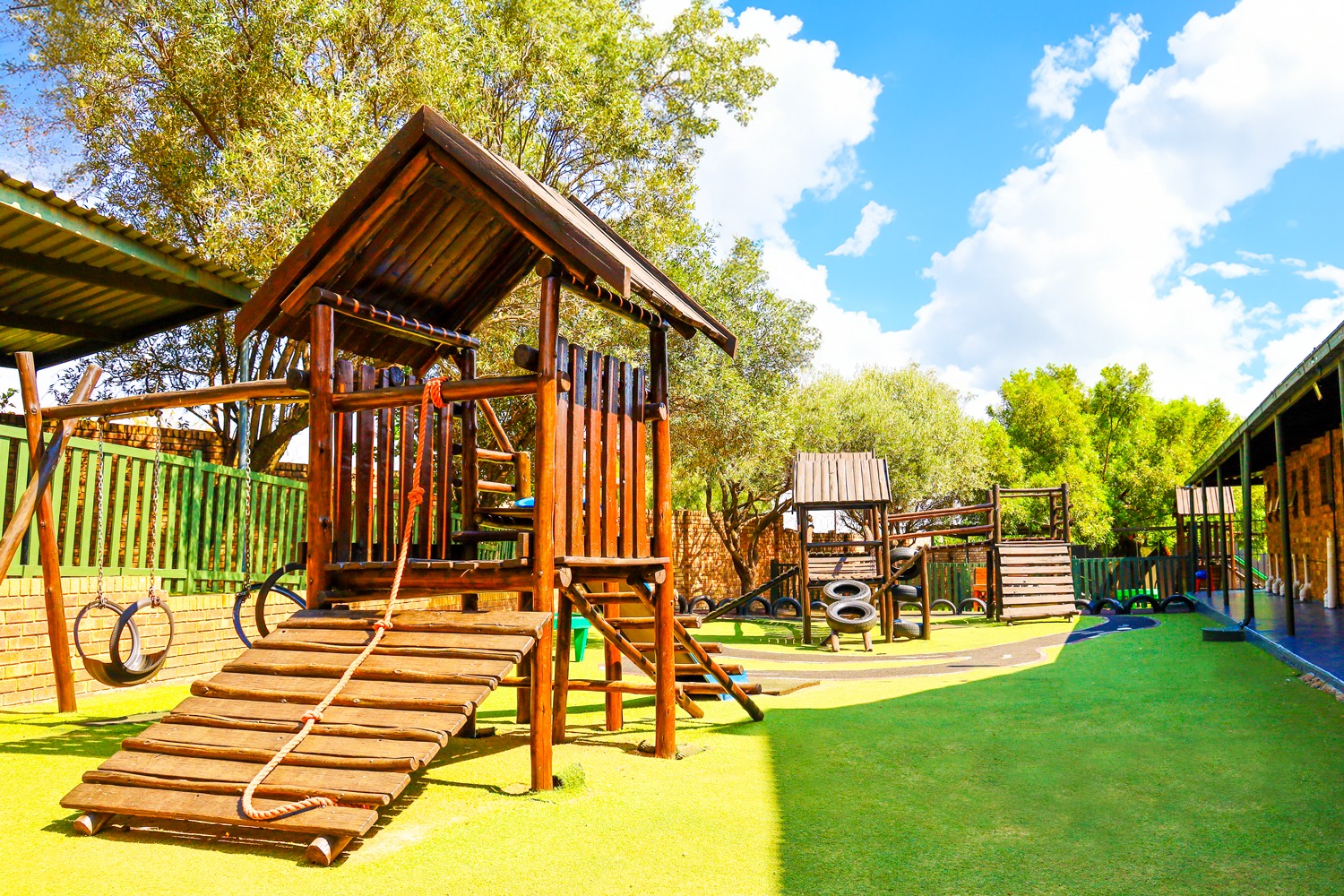 A wooden playground with a house on top of it.