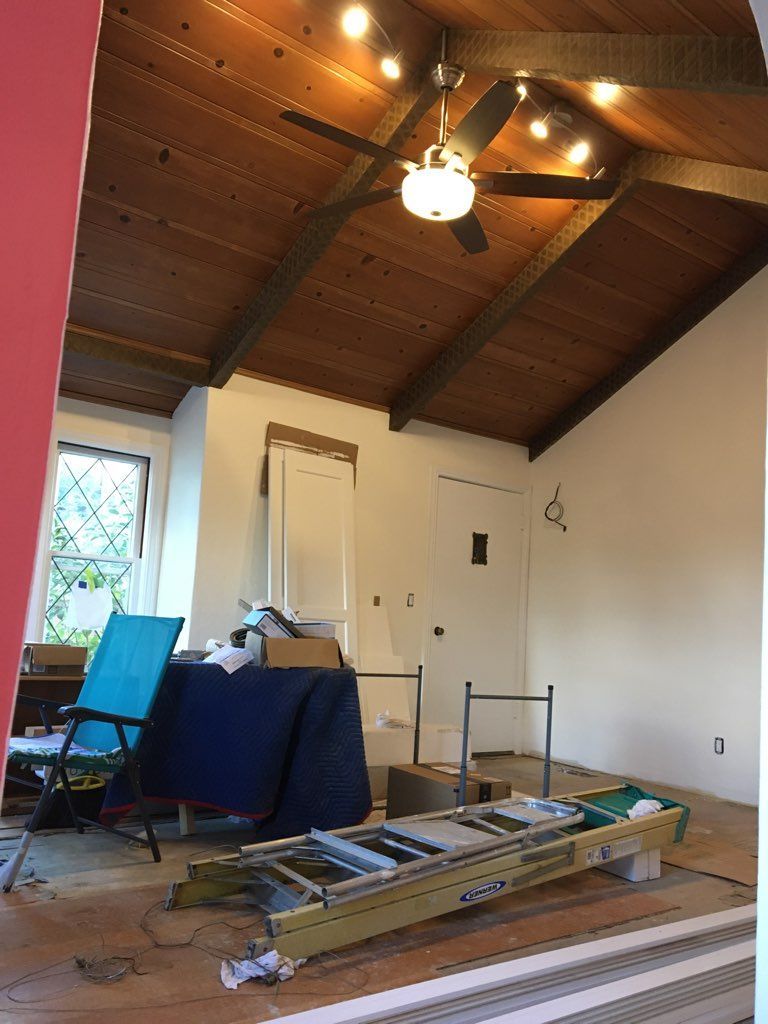 A room with a wooden ceiling and a ladder on the floor.