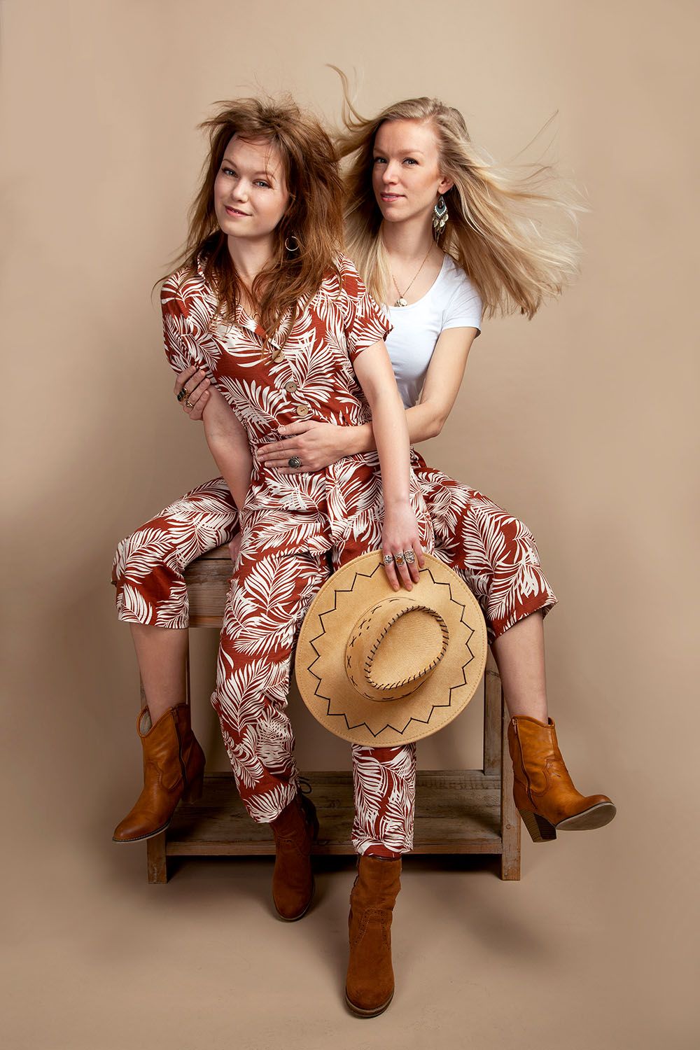 Twee vrouwen zitten op een houten kruk. 