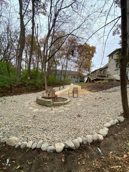 There is a fire pit in the middle of the yard surrounded by rocks.