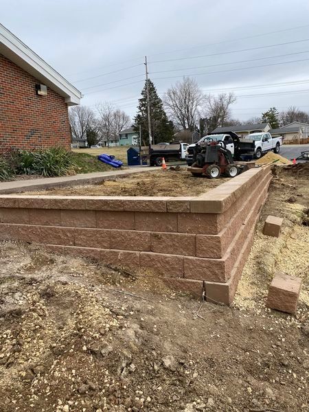 A brick wall is being built in front of a brick house.