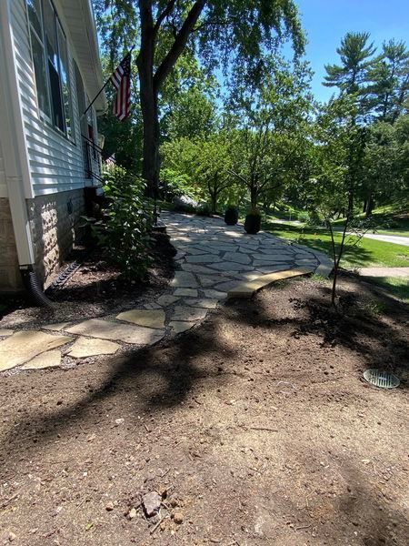 A stone walkway leading to a house with a flag on the side of it.
