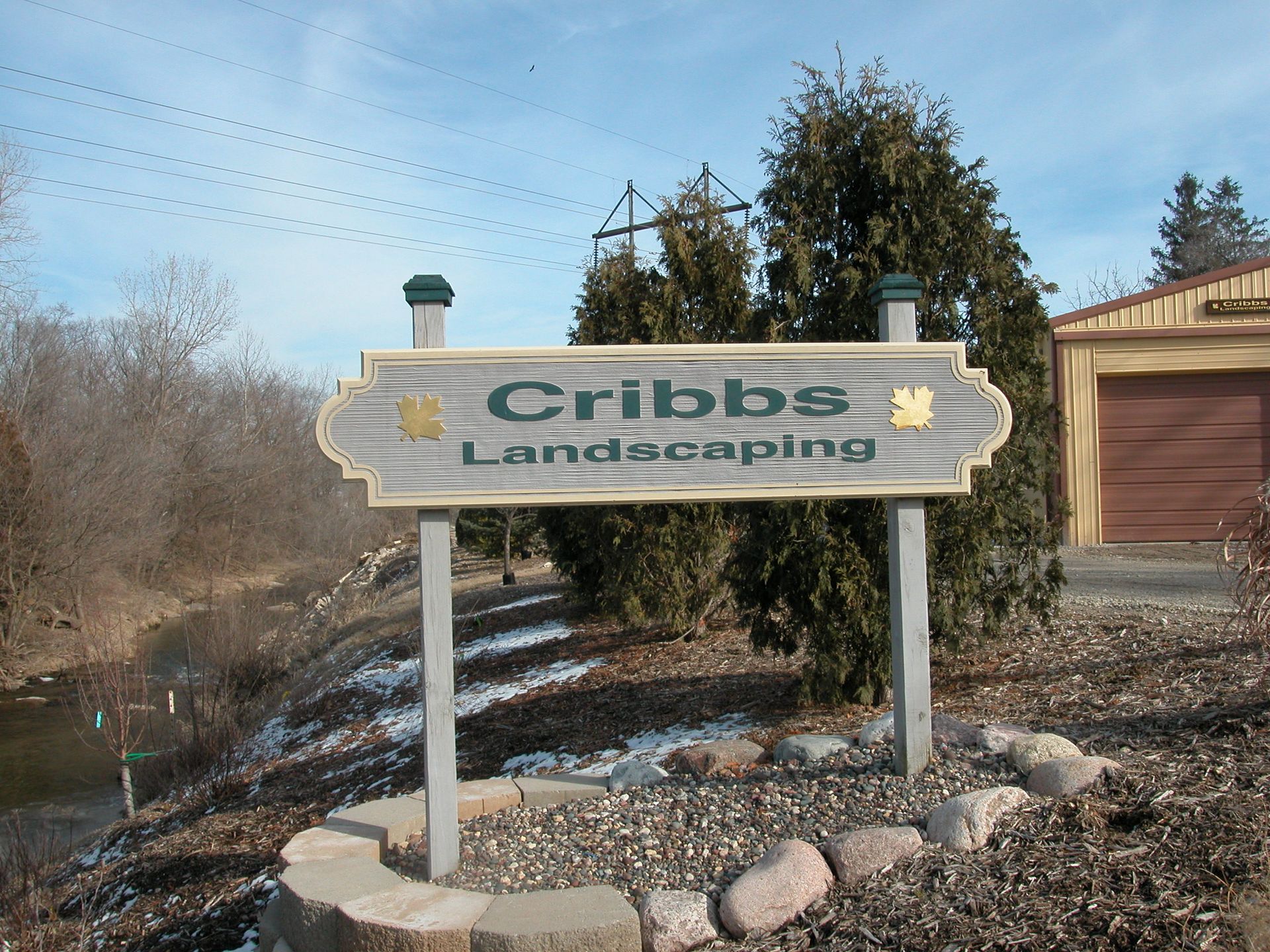 A sign for cribbs landscaping is in front of a garage