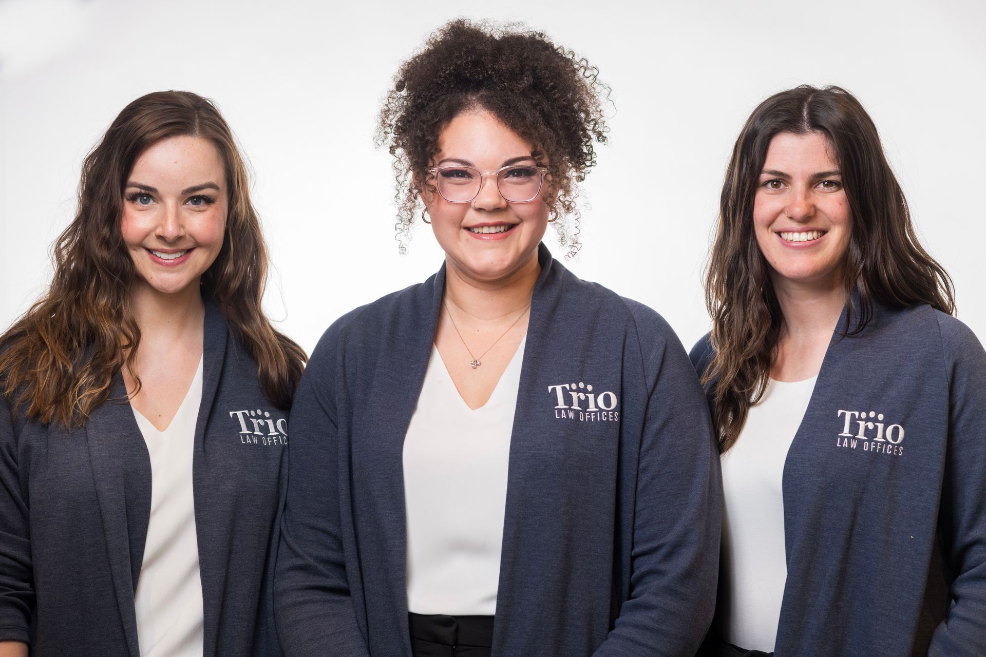 Three women wearing sweaters with the word trio on them are posing for a picture.