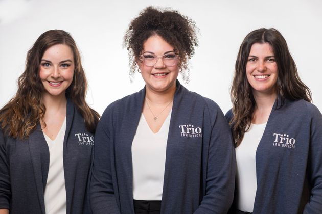 Three women wearing sweaters with the word trio on them are posing for a picture.