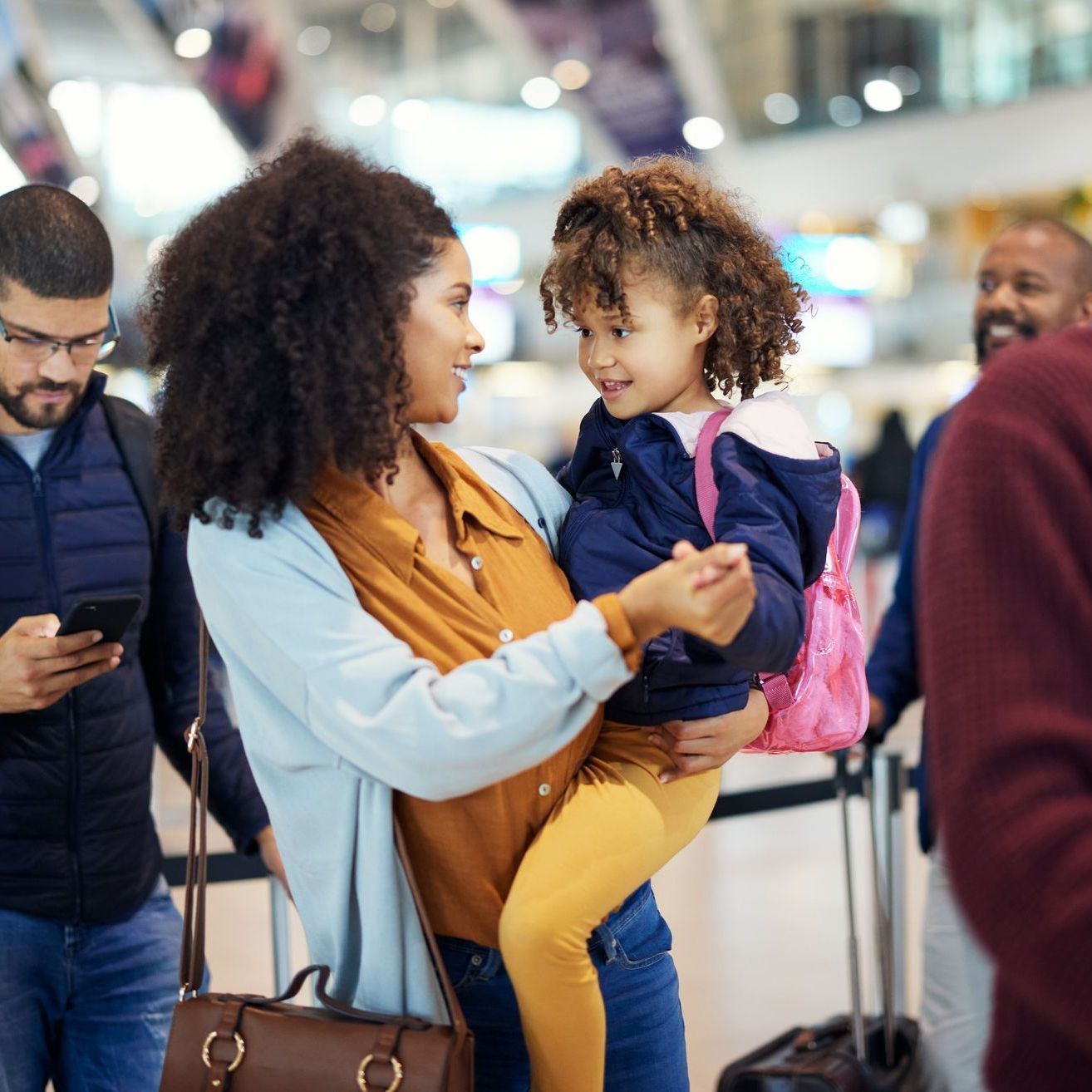 A woman is holding a little girl in her arms at an airport.