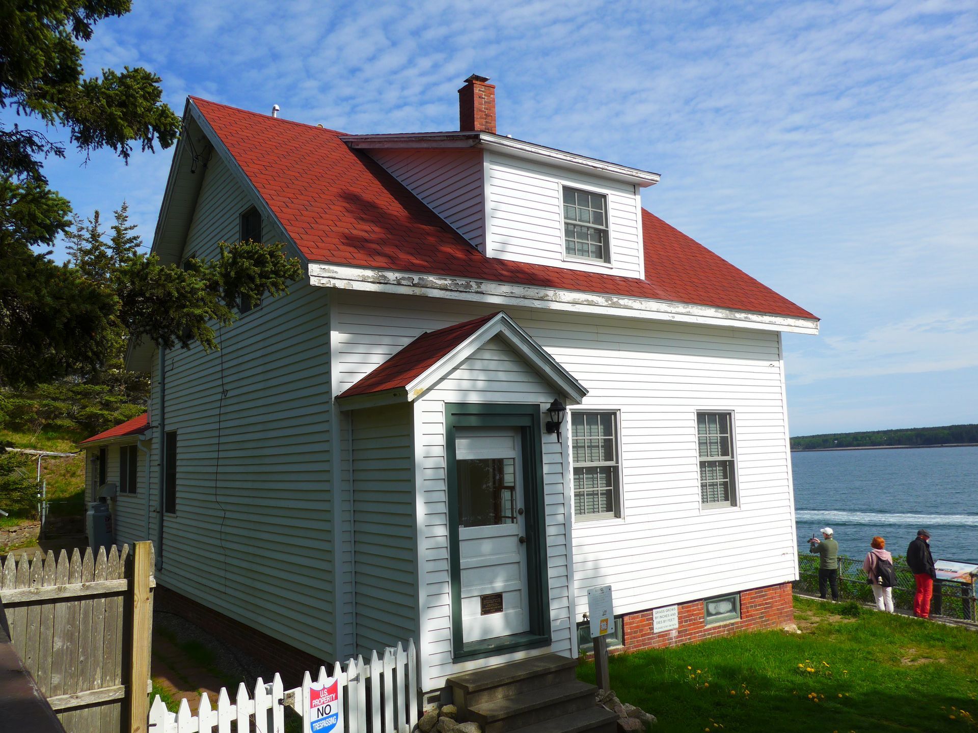 A white house with a red roof and a white picket fence