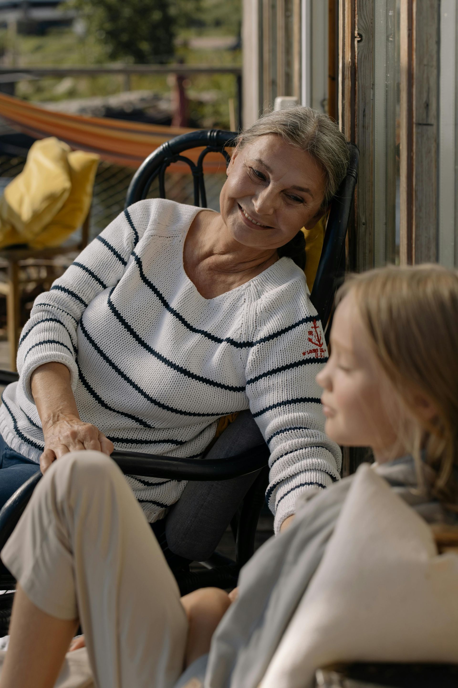 An elderly woman is sitting in a chair talking to a young girl.