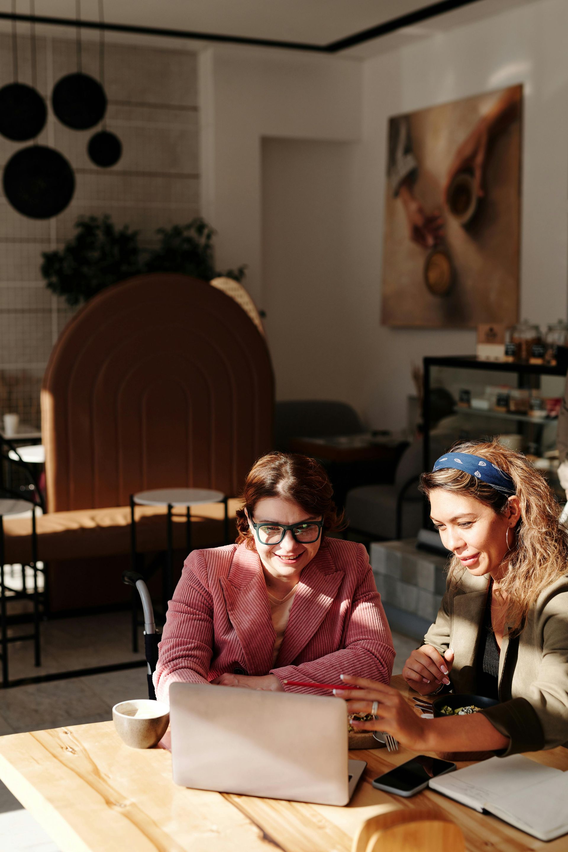 Two women are sitting at a table looking at a laptop.