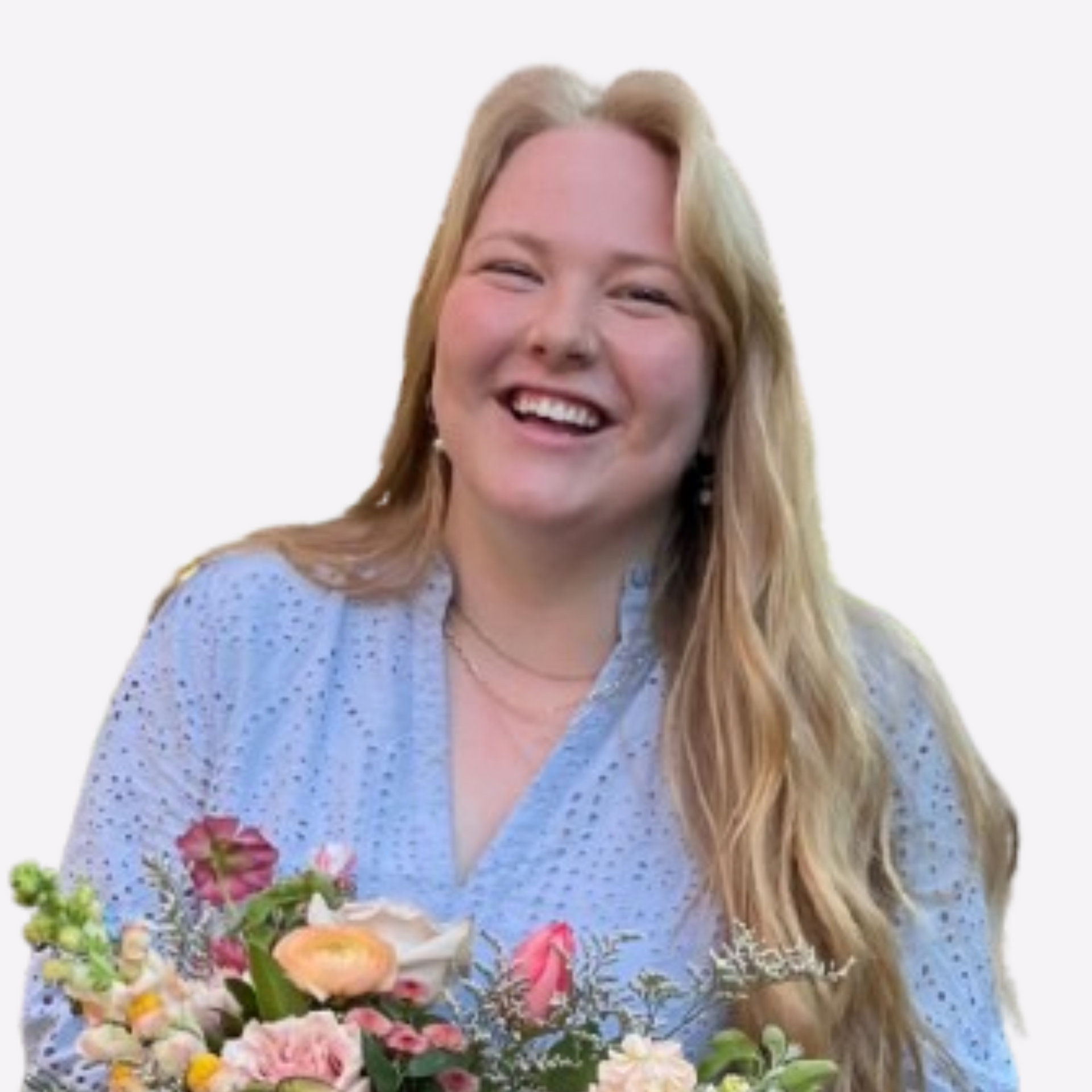 A woman in a blue shirt is holding a bouquet of flowers and smiling.