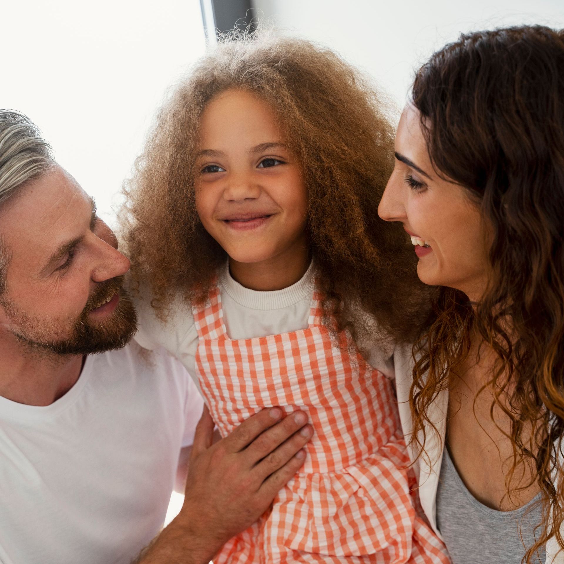 A man and woman are holding a little girl in their arms.