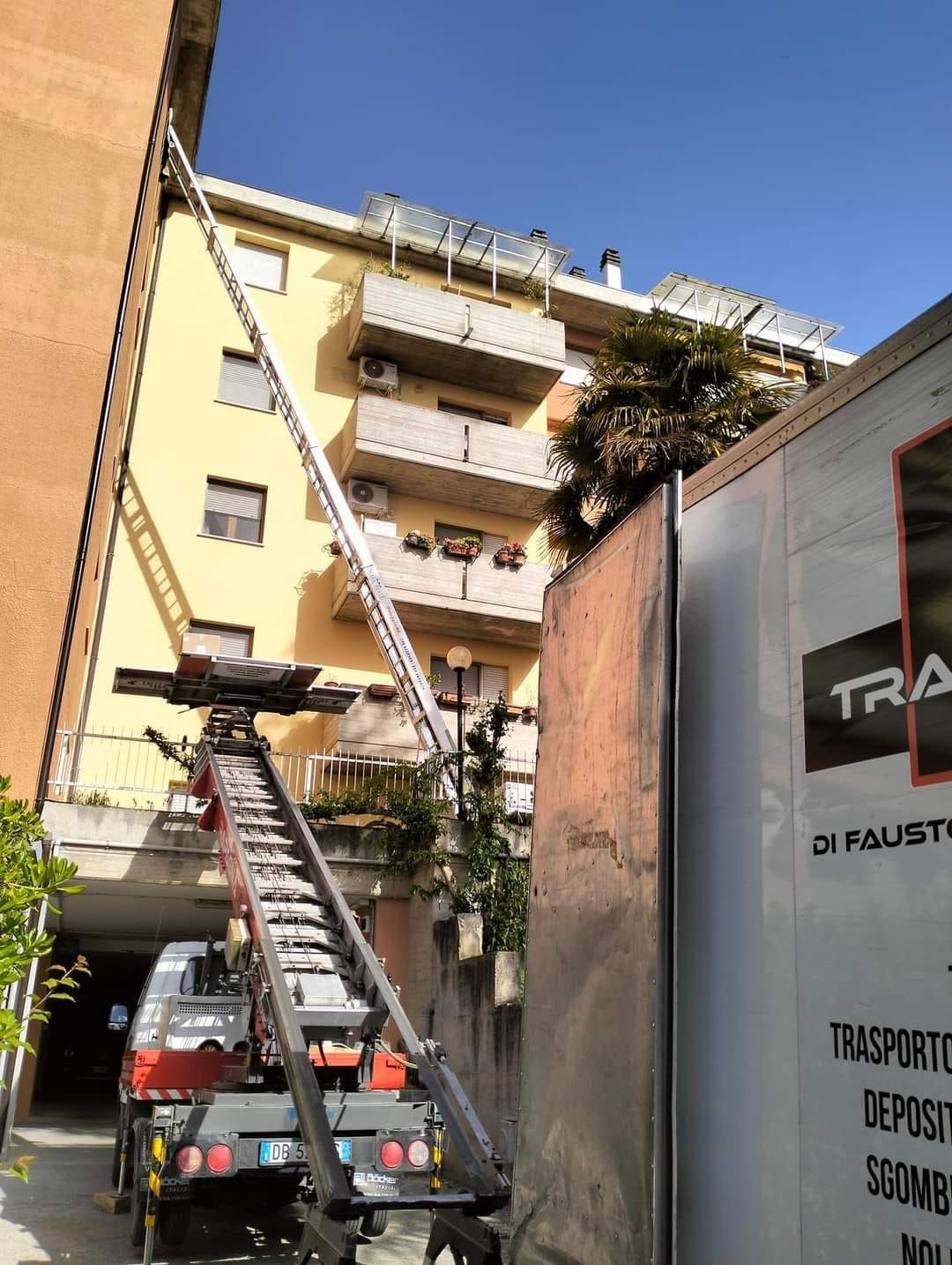 Un camion con una scala attaccata è parcheggiato davanti a un edificio.