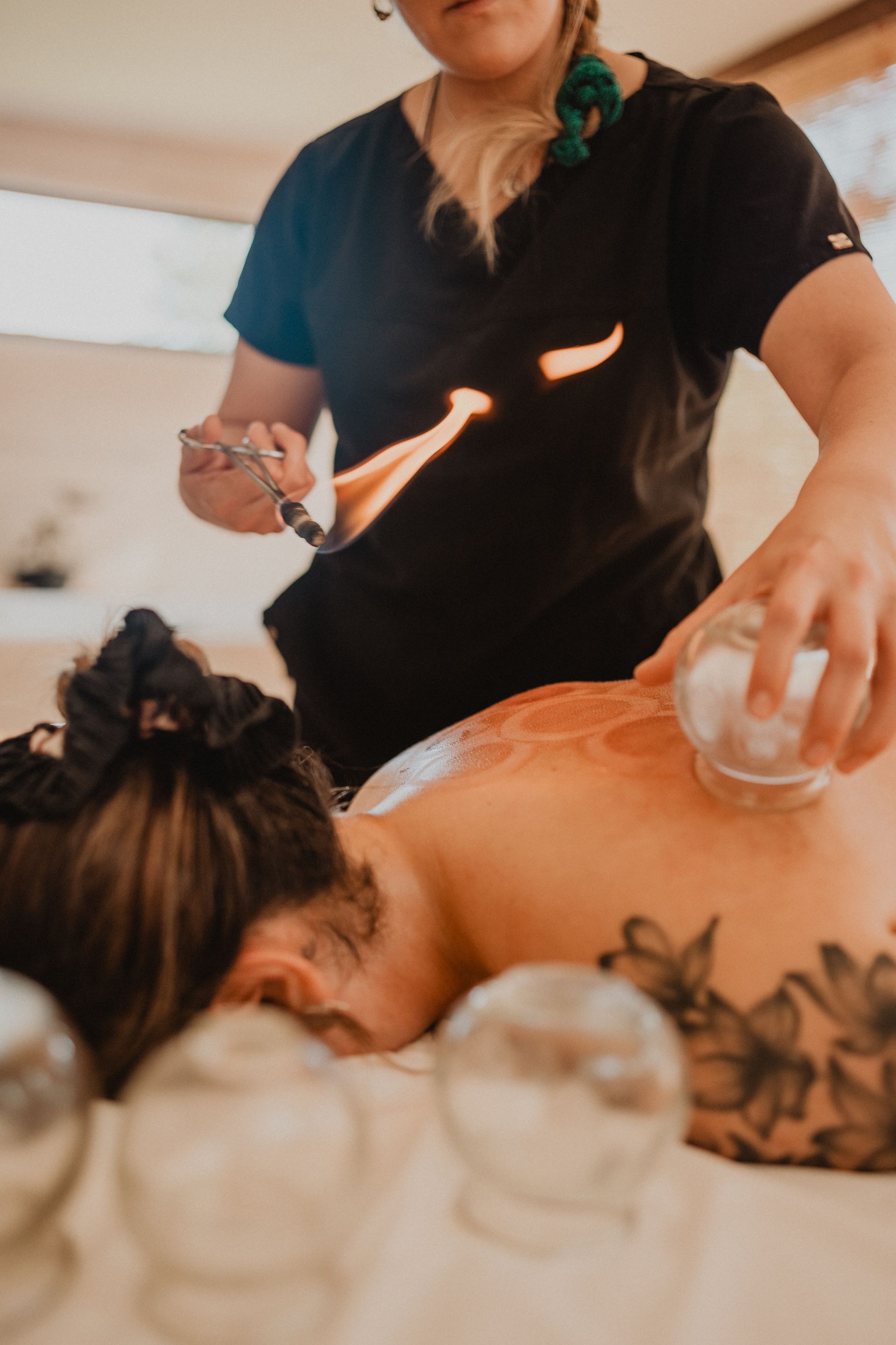 Masajista utilizando piedras calientes sobre un cliente tumbado boca abajo en una sala de spa.