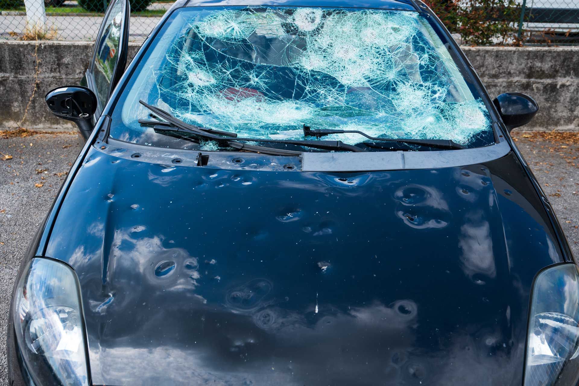 Hail damage to car with damaged hood and windshield