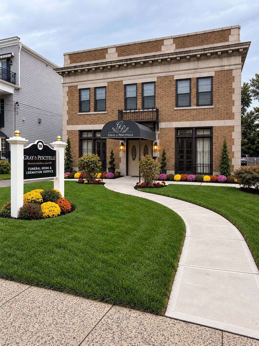 Brick office building with green awnings and landscaping beside a parking lot