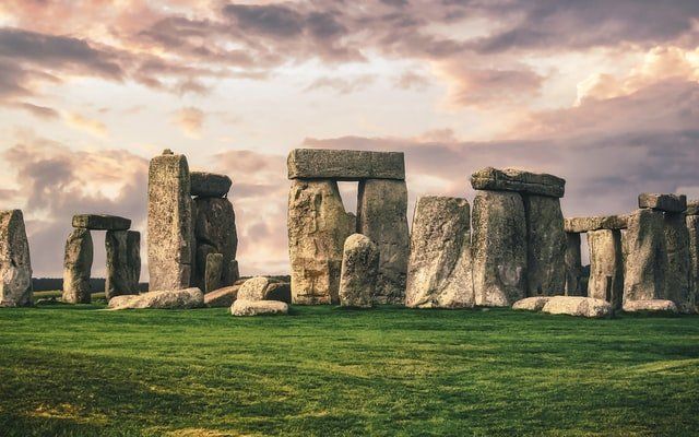 Stonehenge standing stones on a grassy field under a cloudy sunset sky
