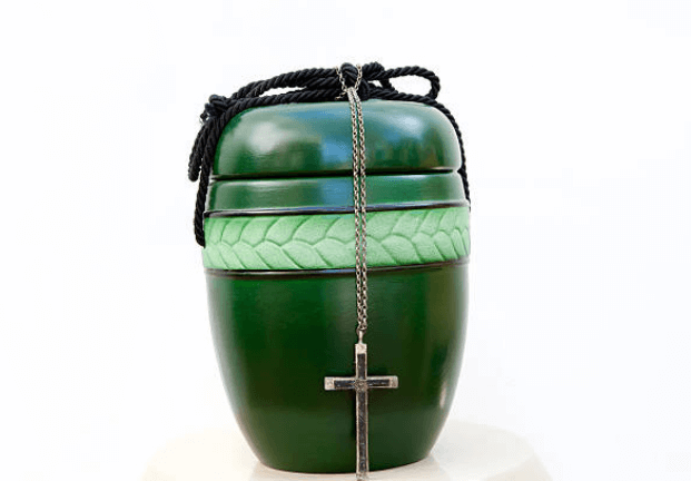Green urn with a cross and chain, topped with braided cord against a white background