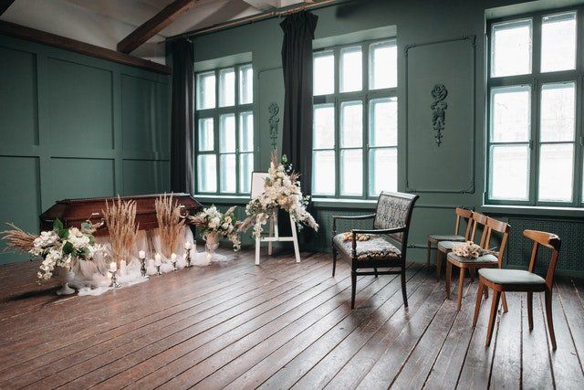 Elegant teal room with wood floors, floral arrangement, and a small seating area by bright windows