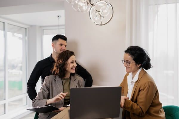 Three coworkers discussing around a laptop in a bright office