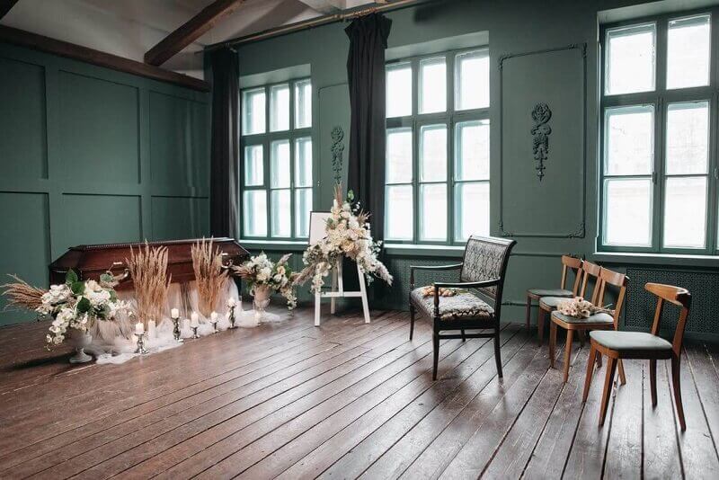 Empty vintage room with teal walls, wooden floors, and a simple wedding ceremony setup near tall windows
