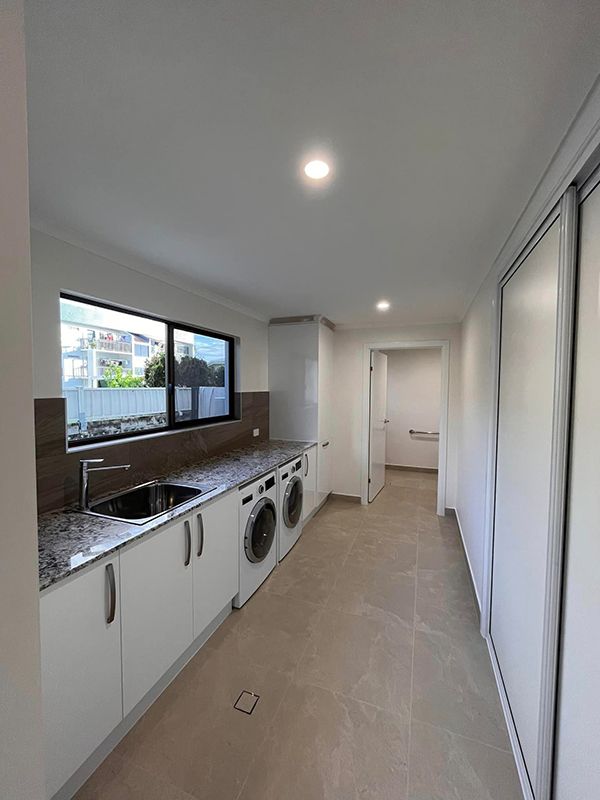 A Laundry Room With A Washer And Dryer, Sink, And Window — DAV Electrical in Kirwan QLD