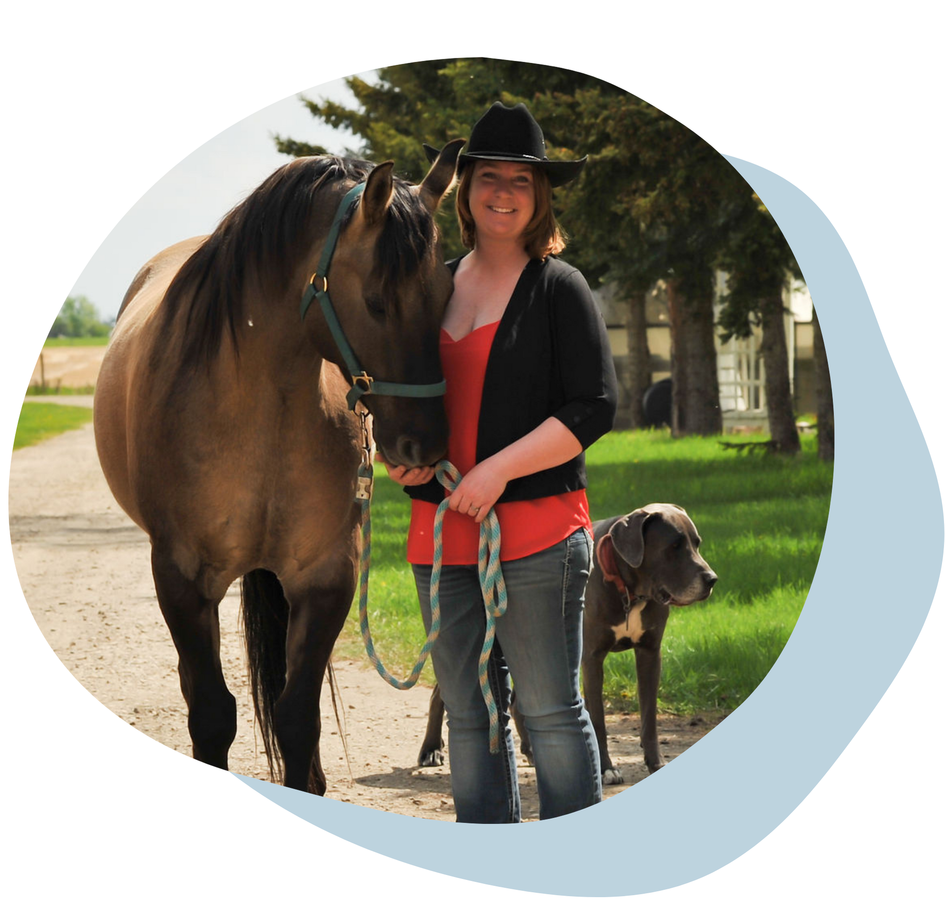 Woman in black hat holding a horse’s reins beside a dog on a sunny path outdoors
