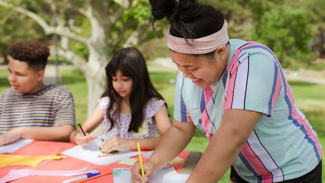 Children drawing on paper at a table with colored pencils in a classroom setting
