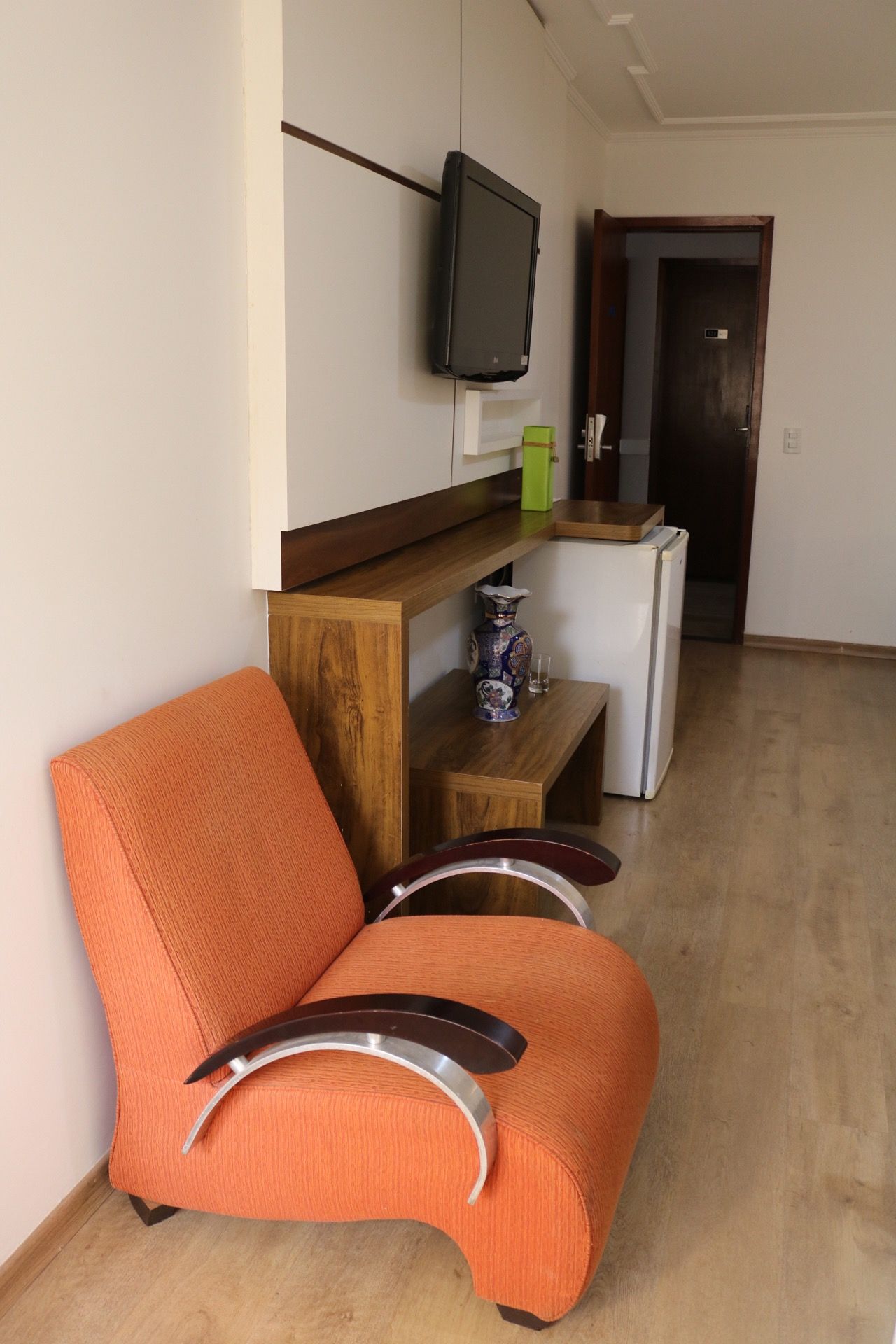 Uma cadeira laranja está em uma sala ao lado de uma televisão.