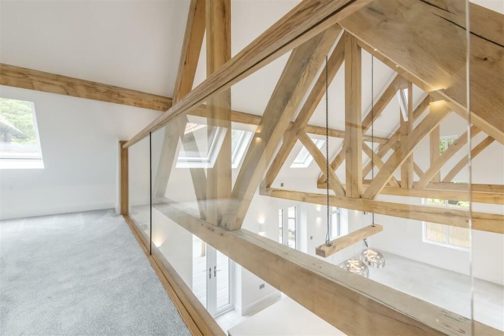 An empty room with a glass railing and wooden beams.