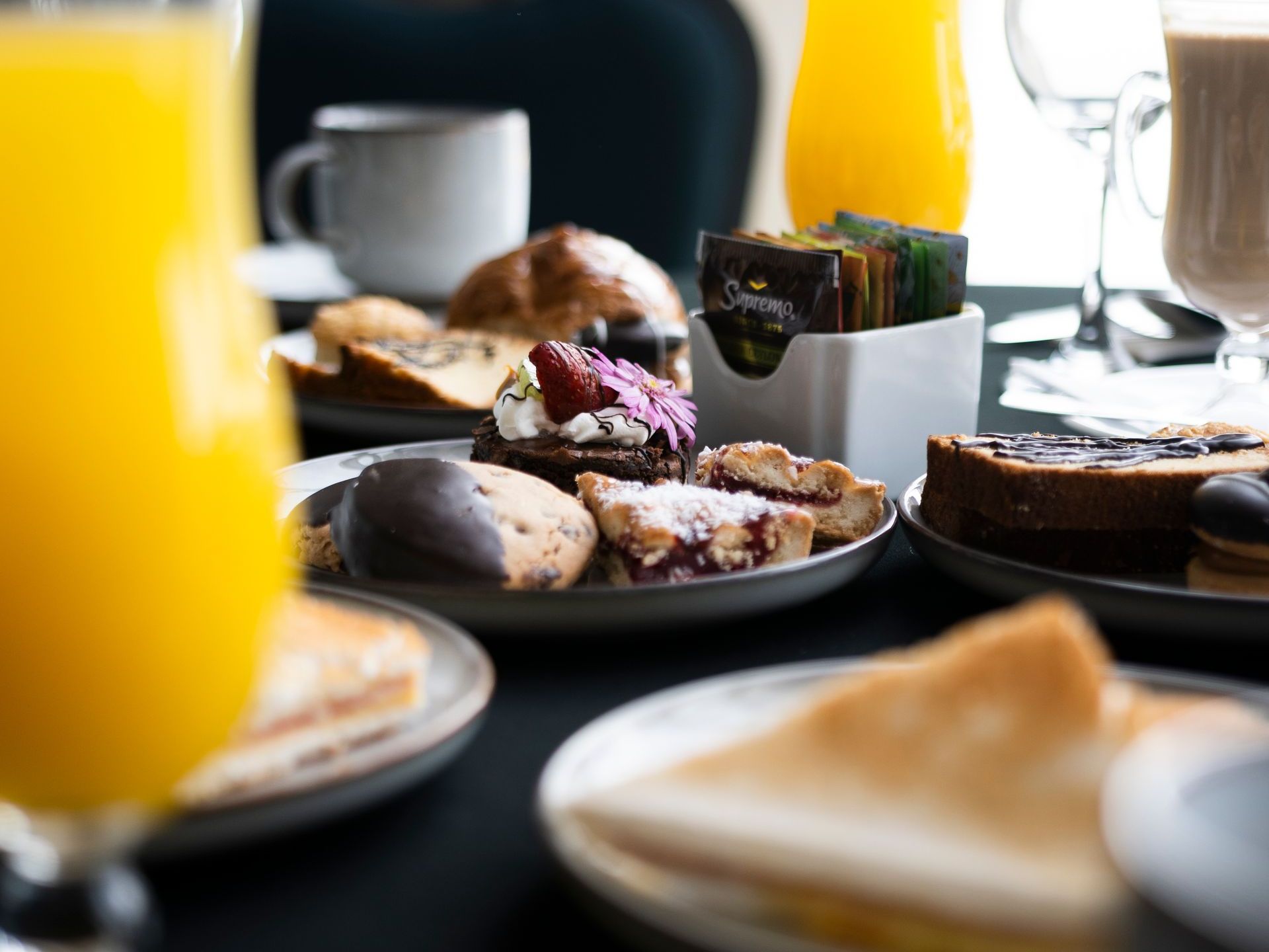 Una mesa cubierta con platos de comida y un vaso de zumo de naranja.