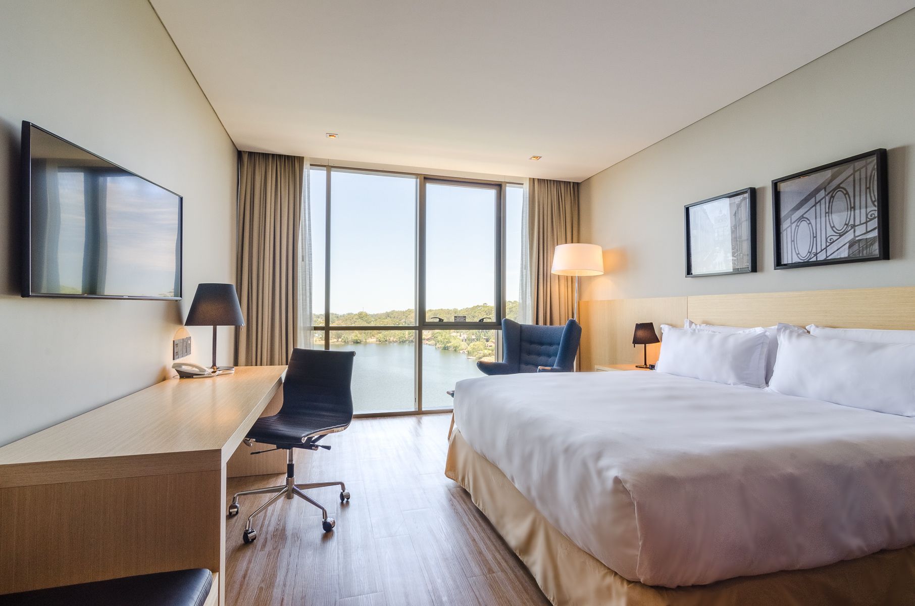 Una habitación de hotel con cama king size, escritorio, silla y televisión.