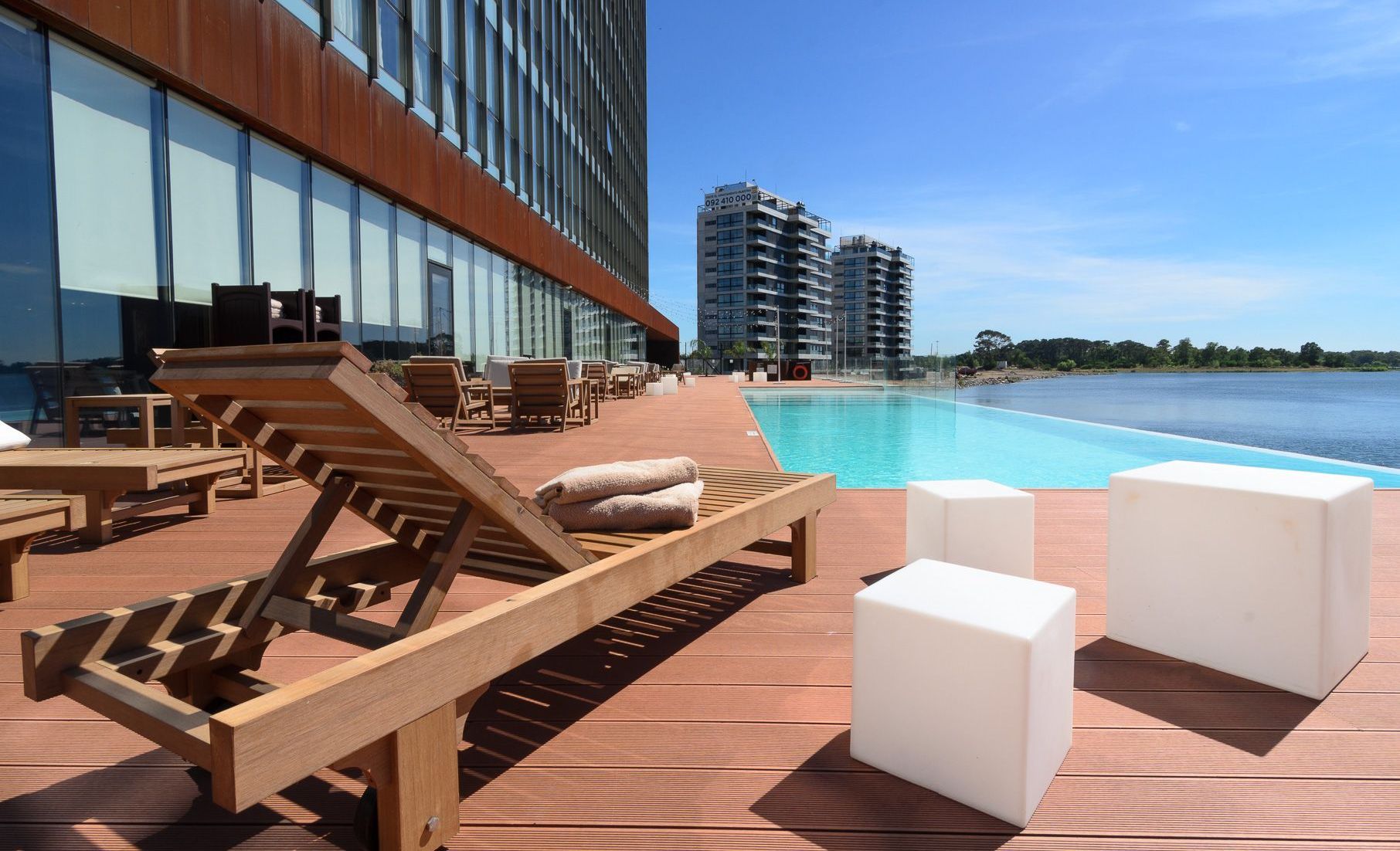 Una terraza de madera con sillas junto a una piscina.