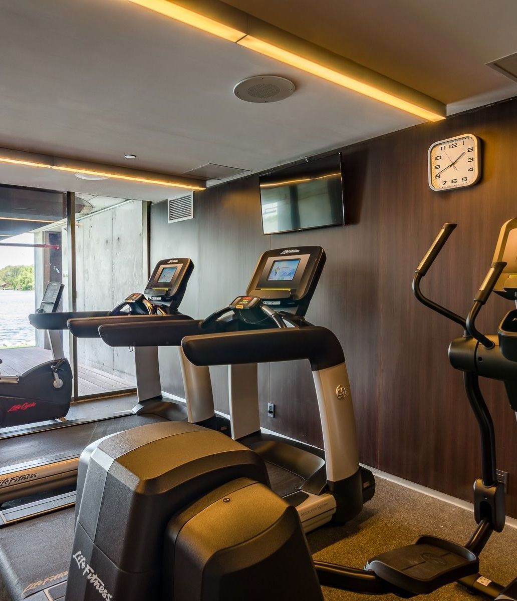 Un gimnasio con cintas de correr y un reloj en la pared.