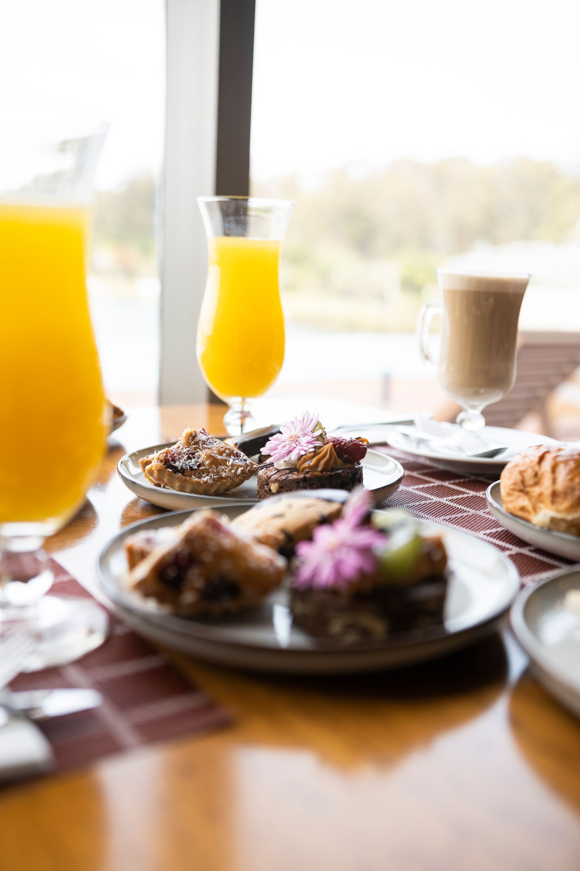 Una mesa cubierta con platos de comida y un vaso de jugo de naranja.