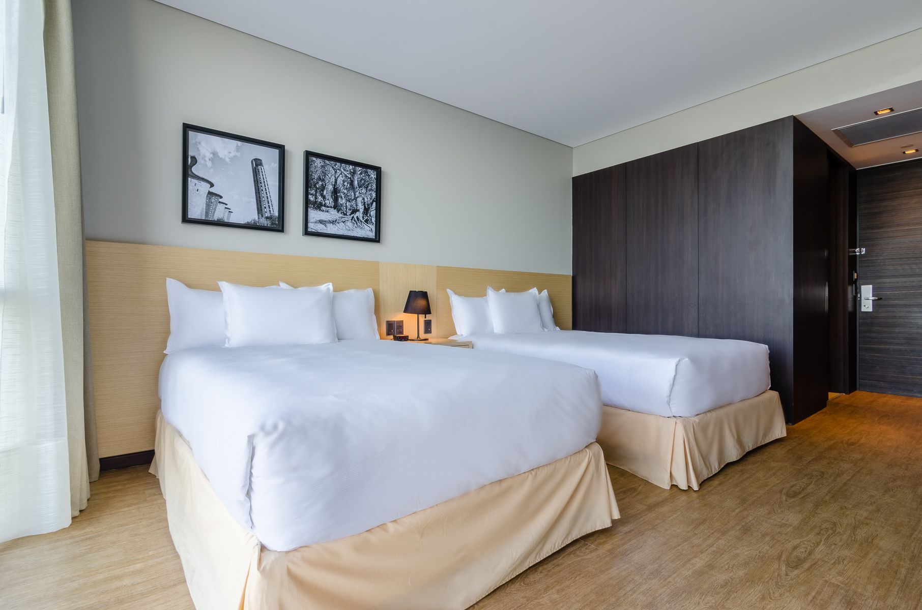 Una habitación de hotel con cama, silla, lámpara y ventana.