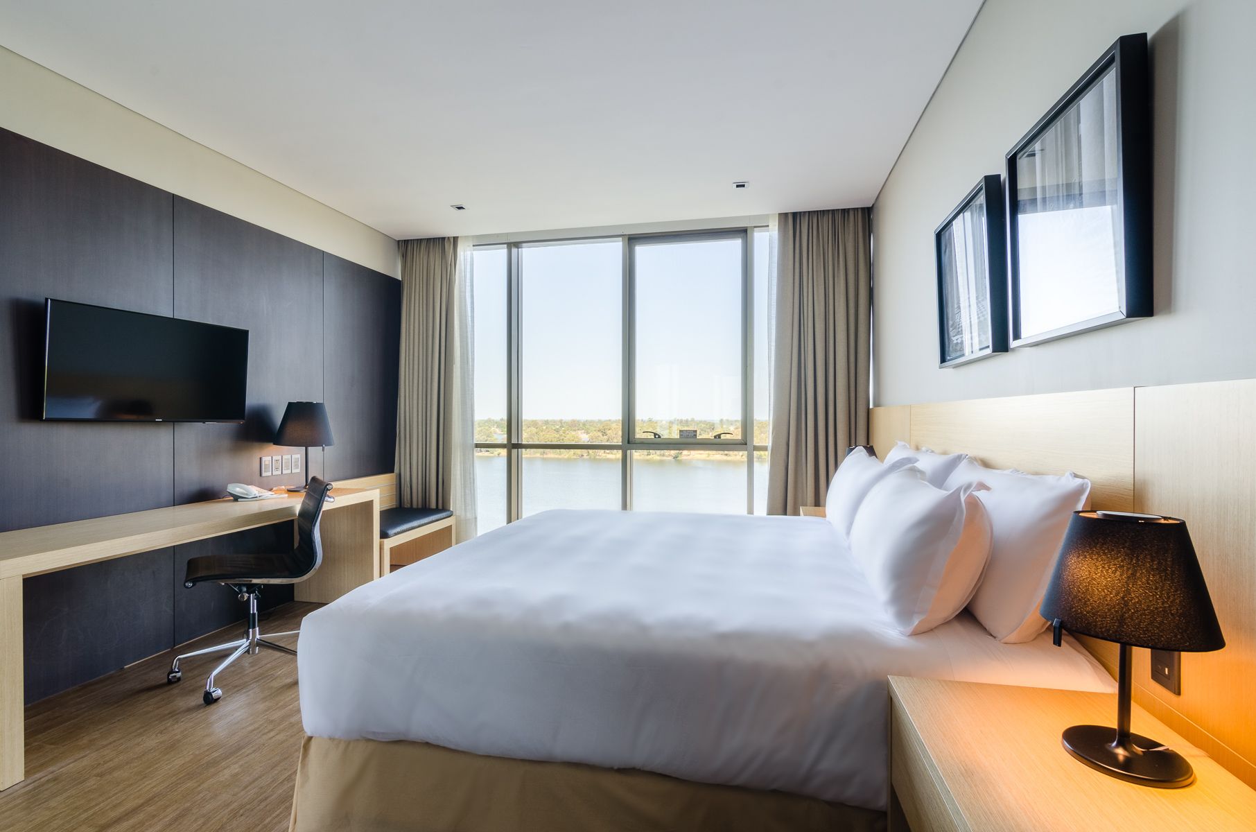 Una habitación de hotel con una cama grande, escritorio y televisión.