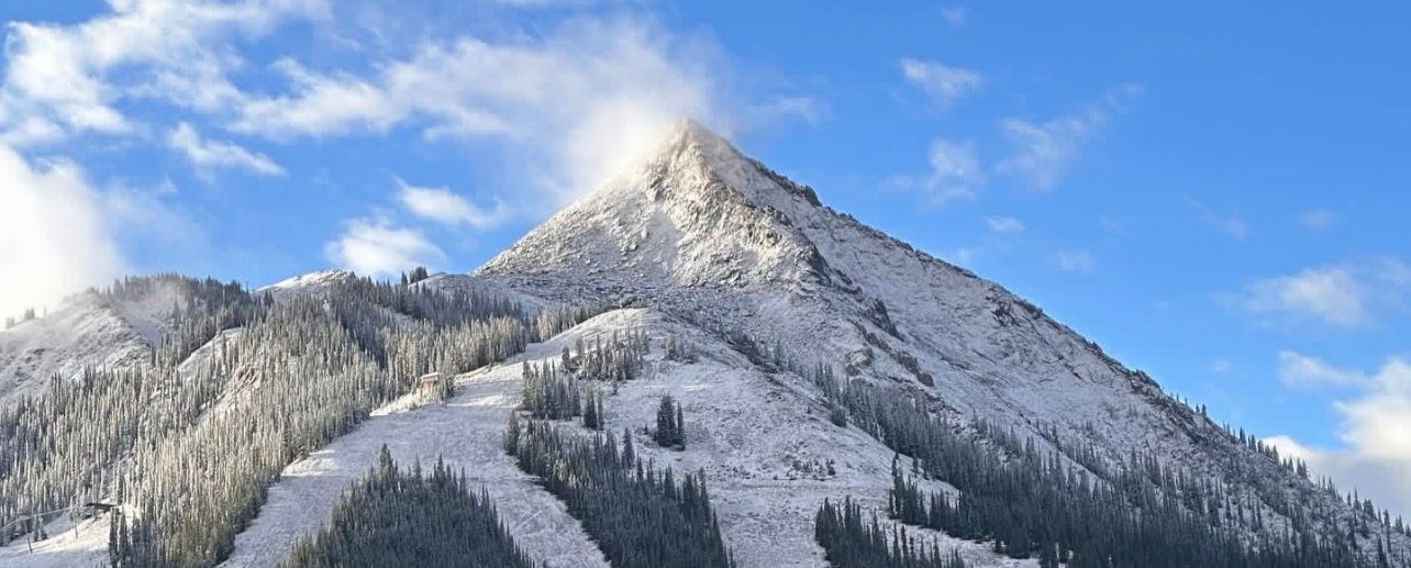 Snow-covered mountain peak under a blue sky with scattered clouds