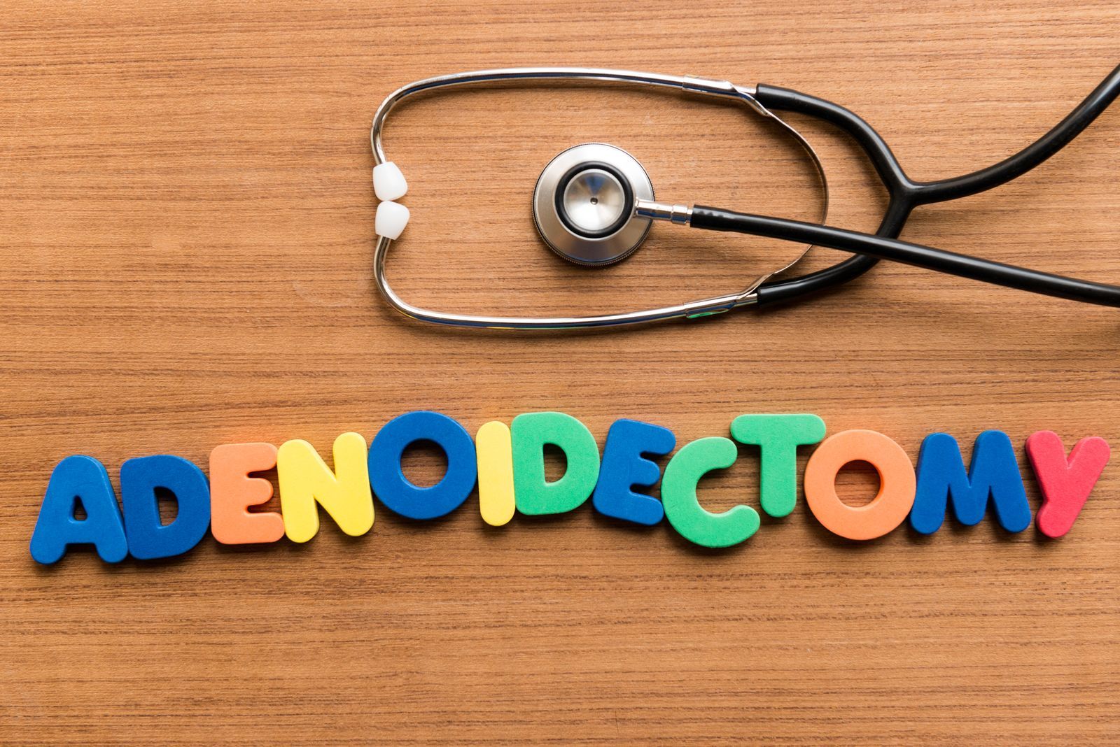 Stethoscope on wood surface next to colorful word 