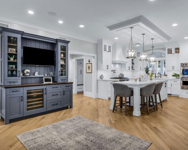 Bright modern kitchen and dining area with blue cabinets, white island, and hardwood floors