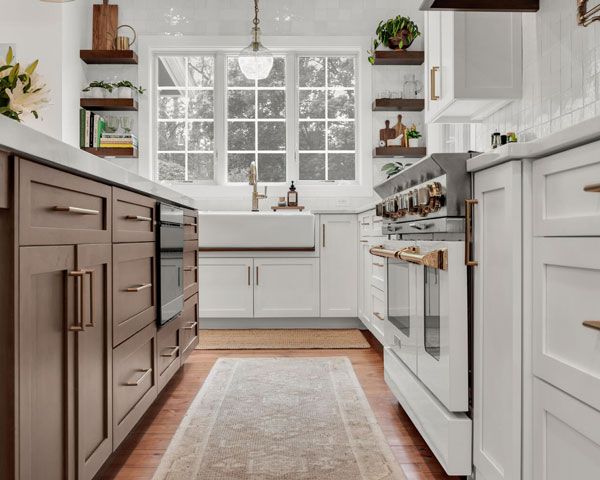 Bright modern kitchen with white cabinets, wood island drawers, and a window over the sink