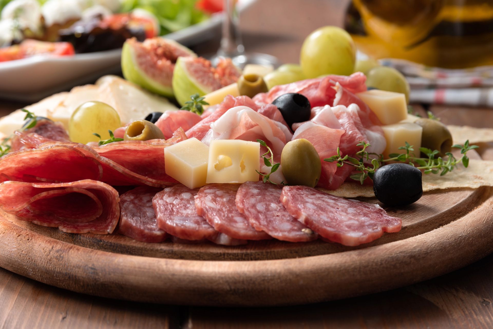 Tagliere di salumi con salame, formaggio, olive, uva e fichi.