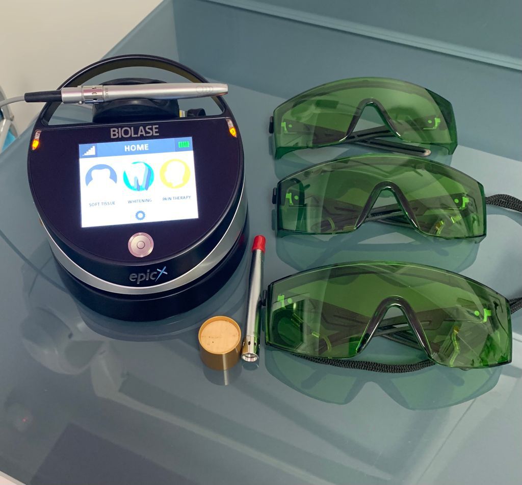 Un dispositivo laser Biolase Epic X con accessori, tra cui occhiali di sicurezza, su un bancone.