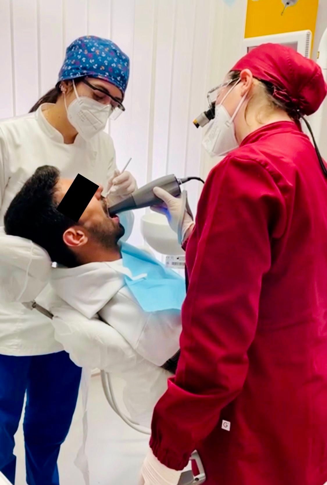 Dentista che utilizza uno scanner digitale su un paziente, assistito da un assistente dentale in una clinica.
