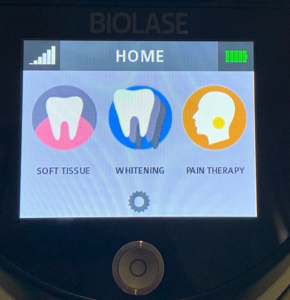 Schermata iniziale del dispositivo laser dentale con opzioni: tessuti molli, sbiancamento, terapia del dolore.