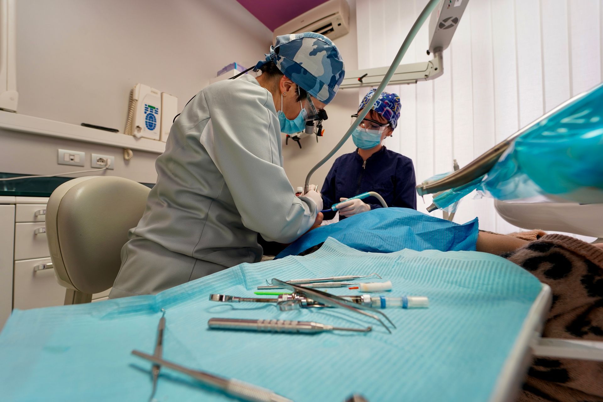 Un dentista esamina la bocca di un paziente insieme a un assistente in uno studio dentistico.